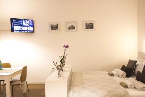 Habitación con cama, mesa y TV en la pared. en Milano Center White, en Milán