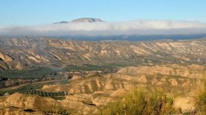 a view of a mountain range with clouds in the background at Cuevas el Torriblanco in Gorafe