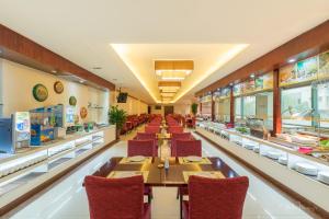 restauracja z długimi stołami i czerwonymi krzesłami w obiekcie Grand Metropark Hotel Shandong w mieście Jinan