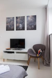 a bedroom with a chair and a tv and some pictures at Willow Pillow Nowowiejska in Warsaw