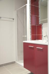 La salle de bains rouge est pourvue d'une douche et d'un lavabo. dans l'établissement West Appart' Hôtel, à Bessines