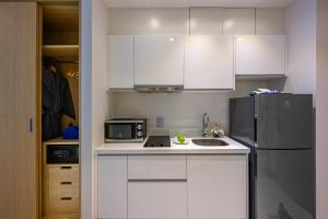 a kitchen with white cabinets and a refrigerator at The Beachfront Hotel Phuket in Rawai Beach