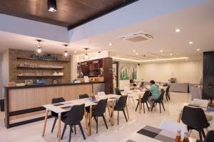 a restaurant with tables and chairs and a man sitting at a counter at River Front Krabi Hotel in Krabi