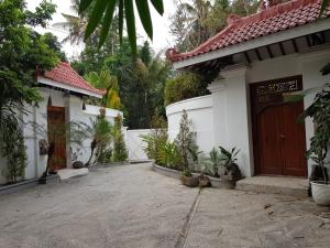 a white house with a brown door and some plants at Yogyakarta Tropicana Villa in Yogyakarta