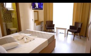 um quarto com uma cama e duas cadeiras e uma televisão em GÜVEN HOTEL em Canakkale