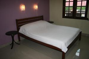 a bedroom with a bed with white sheets and a window at Balai Serama Guesthouse in Kuala Tahan