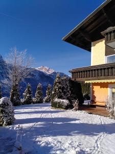 a snow covered yard next to a house with a mountain at Ferienhaus Marianne in Abtenau