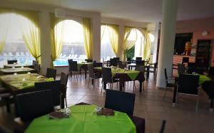 a restaurant with green tables and chairs and windows at Villaggio Alba Chiara in Vieste