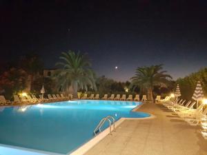 una piscina por la noche con sillas y palmeras en Villaggio Alba Chiara, en Vieste