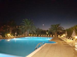 a swimming pool at night with chairs and palm trees at Villaggio Alba Chiara in Vieste
