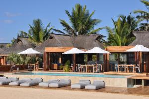 un complejo con una piscina con sillas y sombrillas en Eclectic Beach Retreat en Cabo Nhamua