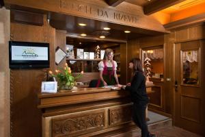 dos mujeres de pie en un bar en un restaurante en Hotel La Serenella, en Moena