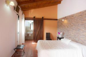 a bedroom with a white bed and a brick wall at FINCA LAS DEHESILLAS in Monesterio