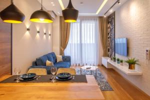 een woonkamer met een tafel en een blauwe bank bij Dali Apartments Pupin Palace in Novi Sad