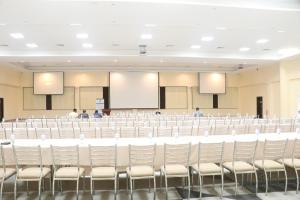 une grande salle de conférence avec des chaises blanches et un podium dans l'établissement Sainte Famille Hotel, à Kigali