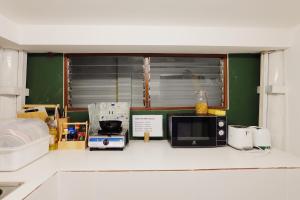 a kitchen counter with a microwave and a window at Barn Laos Hostel in Vientiane