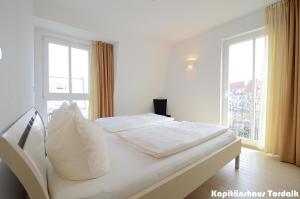 a white bed in a room with a window at Kapitänshaus Tordalk mit 3 Schlafzimmern in Norderney