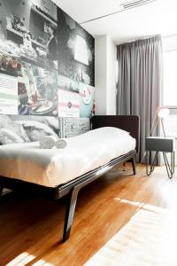 a bed in a room with a wall with pictures at Qbic Hotel WTC Amsterdam in Amsterdam