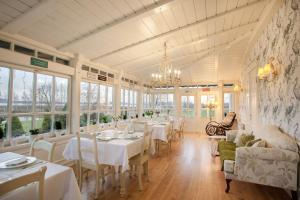 a dining room with tables and chairs and windows at Mioduński Dworek in Ryn