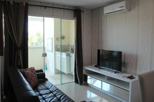 een woonkamer met een bank en een flatscreen-tv bij Praia de Mariscal a 50 metros do mar in Bombinhas