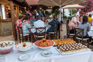 grupa ludzi siedzących przy stole z jedzeniem w obiekcie Castri Village Hotel w mieście Palekastron