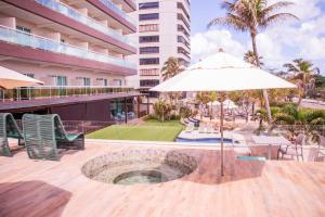 um pátio com um guarda-sol, uma mesa e cadeiras em Crocobeach Hotel em Fortaleza