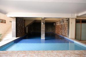 a swimming pool with blue water in a building at RedDoorz Plus at Hotel Srikandi Kendari in Kendari