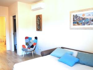 a white bedroom with a bed and a chair at Sogno Azzurro - ArgonautiVacanze in Porto Azzurro