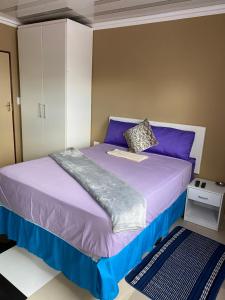 a bedroom with a bed with purple sheets and a cabinet at Ext4 Guest house in Roodepoort