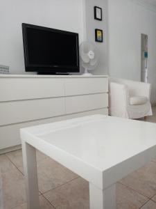 ein Wohnzimmer mit einem TV und einem weißen Tisch in der Unterkunft Apartment close to Yumbo,Free parking in Playa del Ingles