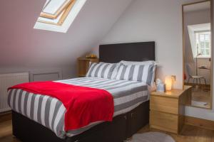 a bedroom with a bed with a red blanket and a desk at HomefromHolme Alban House in Saint Albans