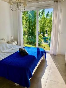 1 dormitorio con cama azul y ventana grande en Palmas de la Pedrera maravillosa casa, en Rocha