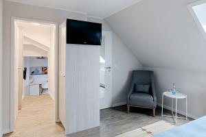 Habitación con TV en una pared junto a una silla en Duus Hotel garni en Wyk auf Föhr