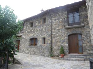 a stone building with a wooden door and windows at Casa Cosculluela in Aínsa