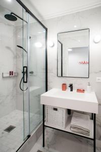 a white bathroom with a sink and a shower at SUITE GIDE : au cœur de la Rive Gauche, neuf, design, 2/4 personnes in Paris