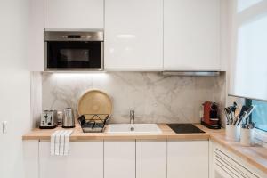 eine Küche mit weißen Schränken und einem Waschbecken in der Unterkunft SUITE GIDE : au cœur de la Rive Gauche, neuf, design, 2/4 personnes in Paris