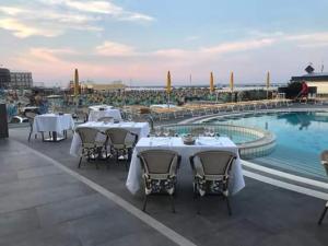 
a large group of people sitting at tables in front of a swimming pool at Hotel David in Cesenatico
