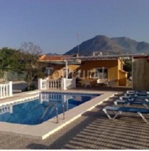 a swimming pool with chairs next to a house at Casa Rural Villa Micleta in Callosa de Ensarriá