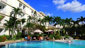 a swimming pool in front of a building with palm trees at Hotel Romeo Palace Pattaya in North Pattaya