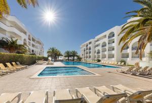 a swimming pool with lounge chairs and a resort at Ukino Terrace Algarve Concept in Armação de Pêra