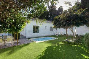 een achtertuin met een zwembad en een tafel en stoelen bij Villa Conchita By Seric,15´ walking to the beach in Torremolinos