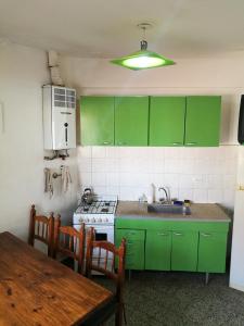 a kitchen with green cabinets and a sink and a table at Casa duplex Frente AL Mar familiar Depto A in Mar del Plata
