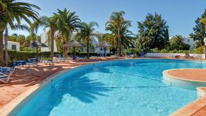 a large swimming pool with palm trees and chairs at Apartment Sao Rafael in Albufeira