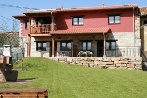 una gran casa roja con una pared de piedra en Apartamentos Vega Rodiles el balcón en Villaviciosa