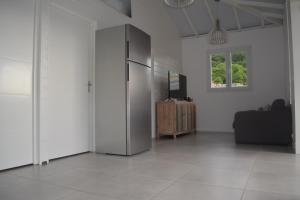 a living room with a refrigerator and a television at Les Lodges de Malendure in Bouillante
