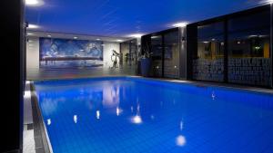 a large swimming pool with blue lighting in a building at Park Plaza Eindhoven in Eindhoven