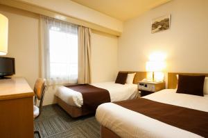 a hotel room with two beds and a television at Shin-Osaka Sunny Stone Hotel in Osaka