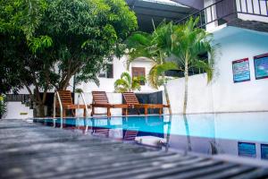 einen Pool mit Stühlen und Palmen neben einem Gebäude in der Unterkunft Lion Resort in Polonnaruwa