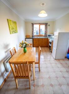 uma cozinha com uma mesa e cadeiras e um frigorífico em Hamish's Cottage em Tobermory