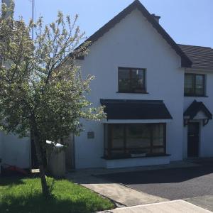 a white house with a tree in front of it at Beach Close Lodge in Kinsale